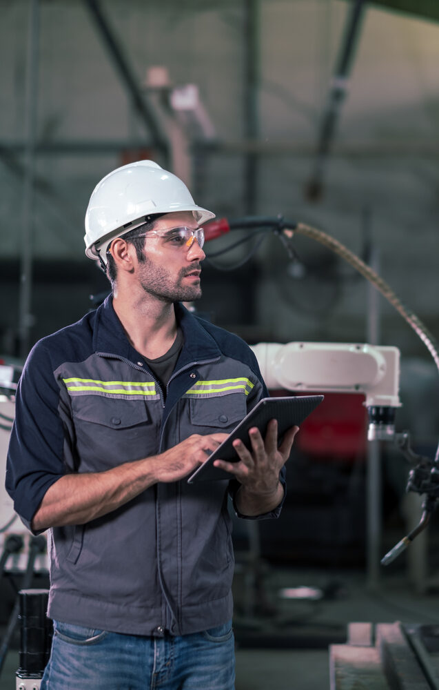 Engineer,Man,Use,Tablet,To,Control,Welding,Robotic,Automatic,Arm